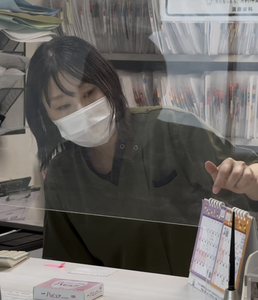 「受付で患者さんの対応をする清藤歯科のスタッフ」